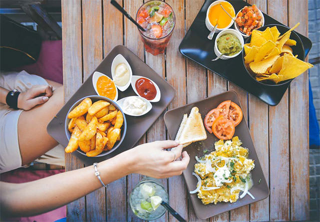 Womans-Hand-Taking-Food-From-Cafe-Table-With-Dips-And-Drinks